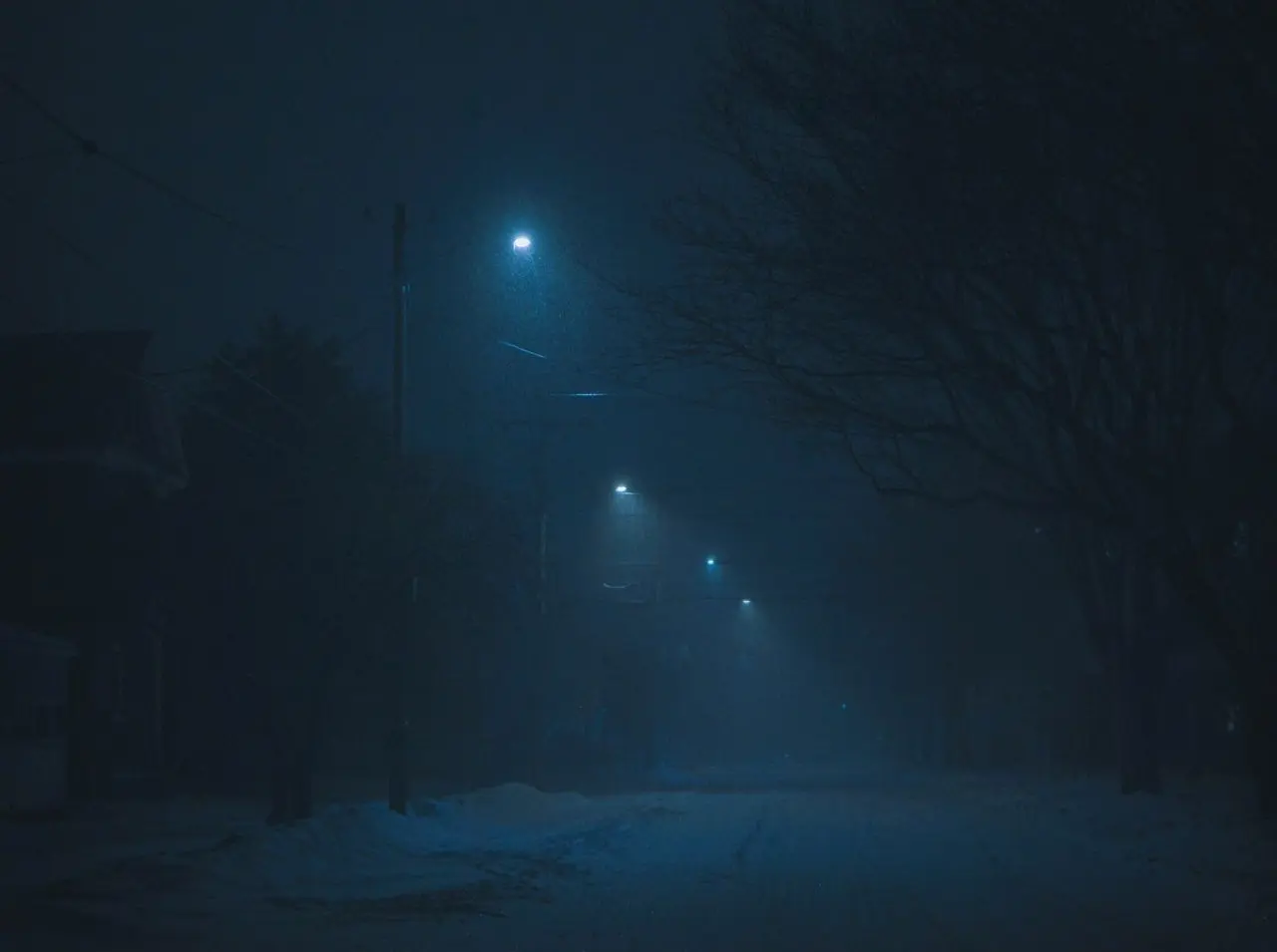 a dark street at night with a street light in the distance
