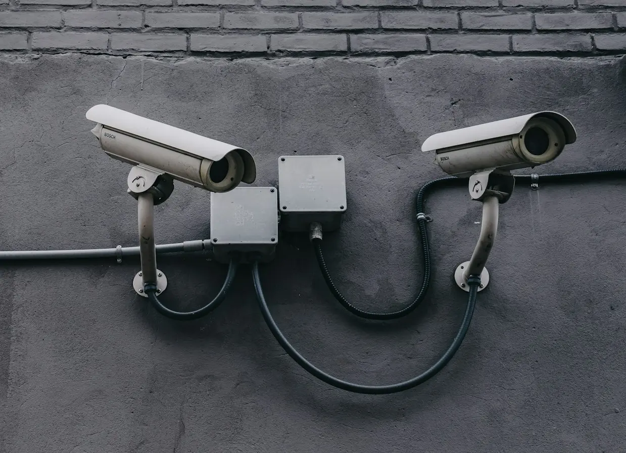 two bullet surveillance cameras attached on wall